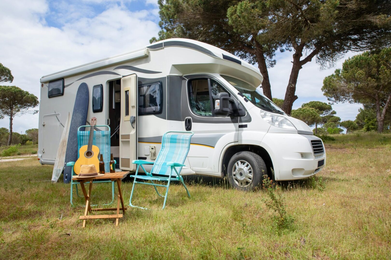 A white rv parked in the grass near trees.