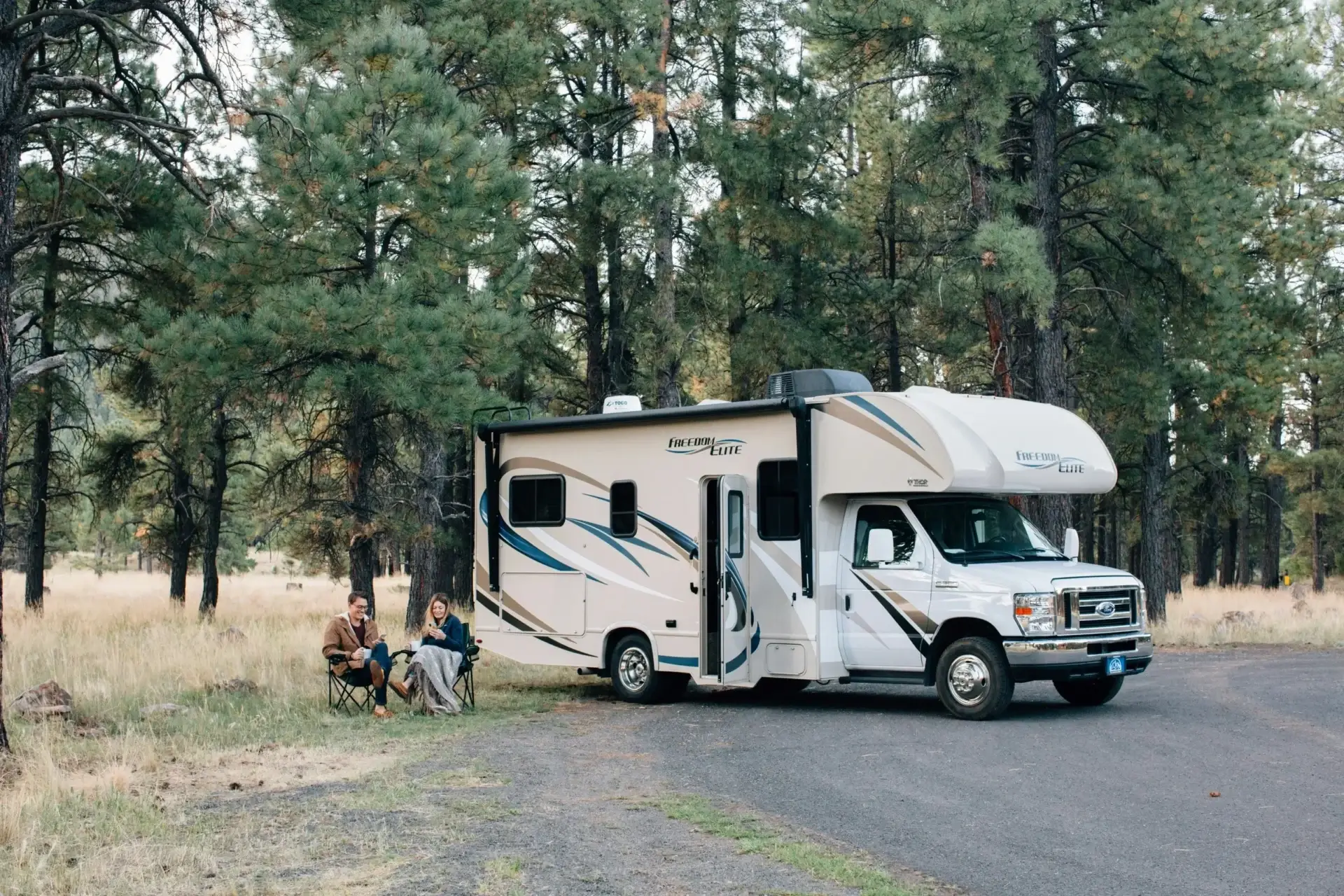 A white and blue rv parked on the side of a road.